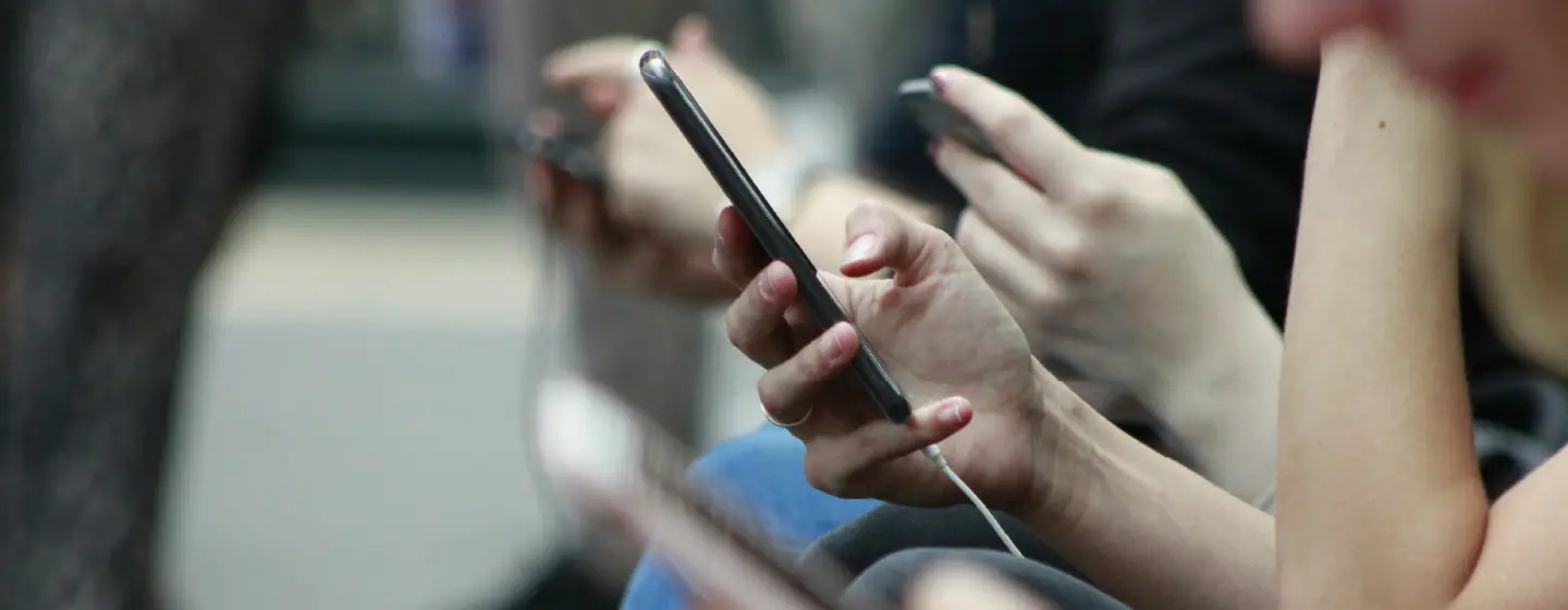 people sat in a line all using smartphones, representing engagement with conversational chatbots for better deeper responses in quantitative research