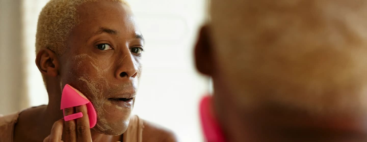 a person cleansing their skin in the mirror representing authenticity in media imagery